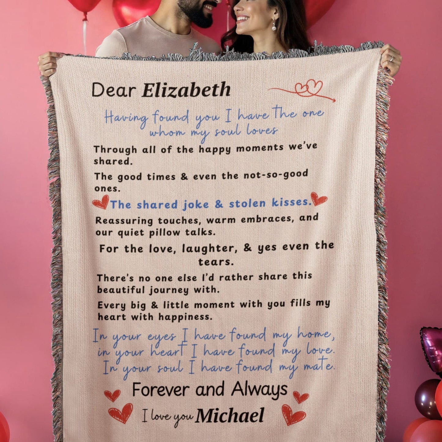 A couple holding A family heirloom blanket it is a love letter. A Personalize Gift with custom names. A couple is hold the blanket up in a Valentine's theme background.