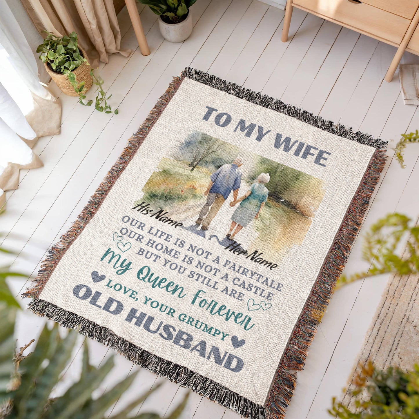 Heirloom Artwork Woven Blanket with a sentalmental message to wife from husband. Blanket is displayed laying on a light gray wooden floor by plants and a window.
