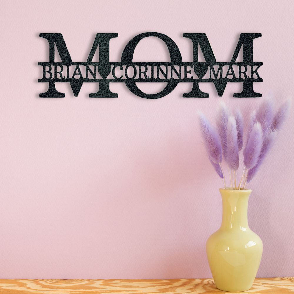 Decorative wall art with 'MOM' and names on a pink wall with a vase of lavender.