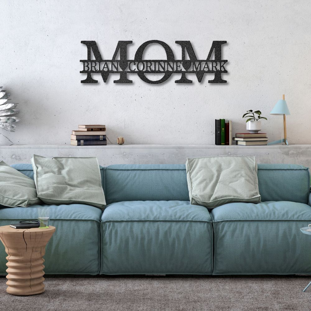 Blue sofa with decorative pillows in a living room setting, featuring a metal wall art piece with 'MOM' and names.