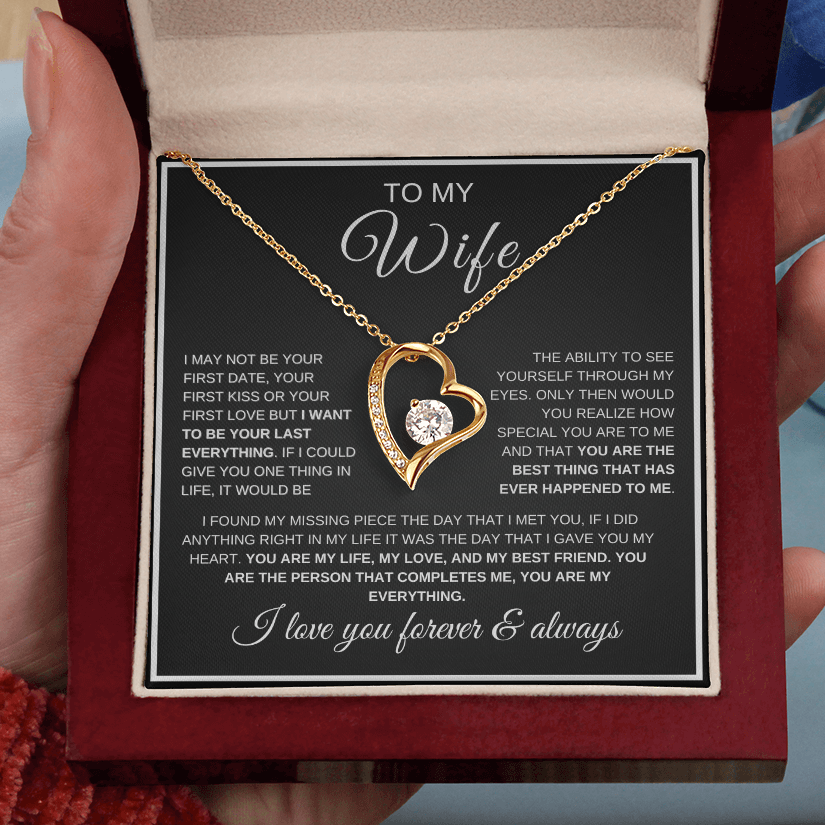 Gold heart-shaped necklace with a message card for 'To My Wife' held in hands.